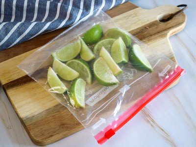 Lime wedges sealed inside a freezer back on top of a wooden chopping board