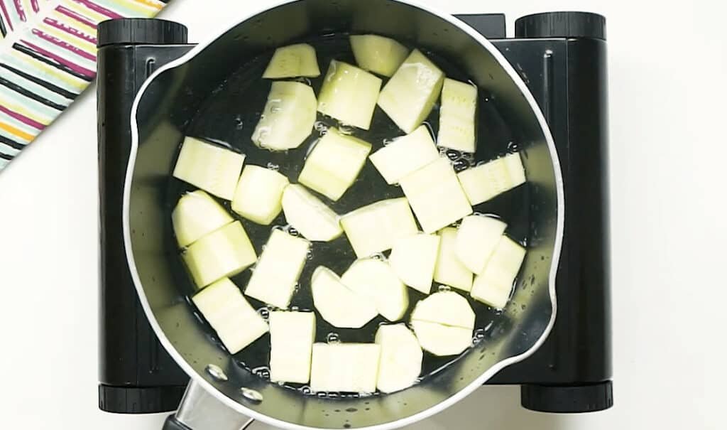 1-inch pieces of peeled courgette in a pot of boiling water being blanched