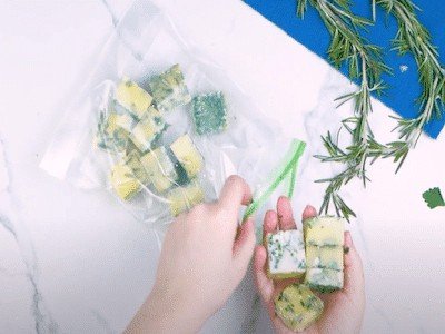 Frozen cubes of coriander and butter being placed into a clear freezer bag